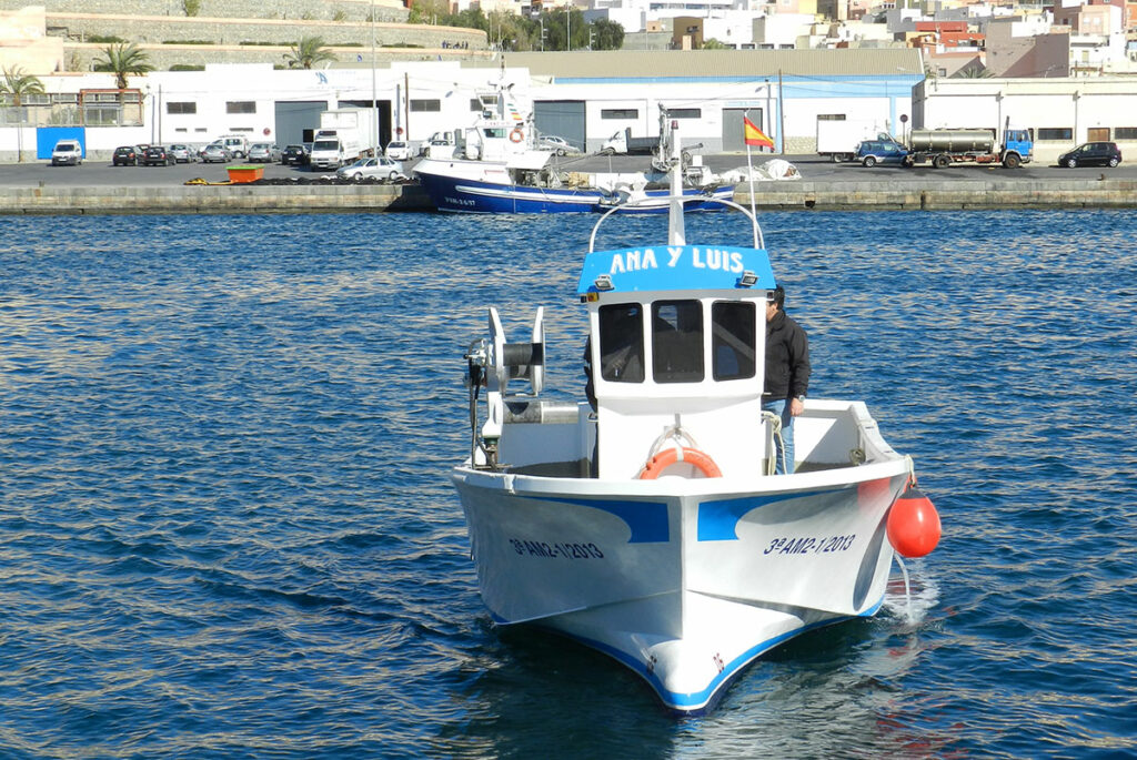 Vista frontal del barco de pesca Ana y Luis navegando por el puerto marítimo.