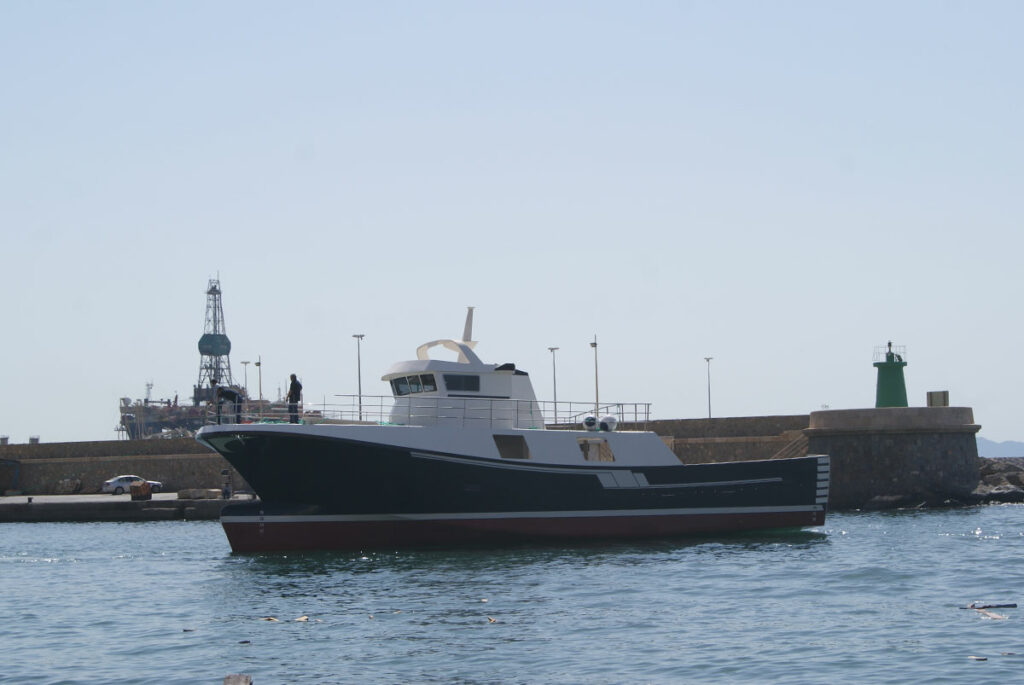 Vista lateral del barco de pesca El Andaloussi navegando por el puerto marítimo.