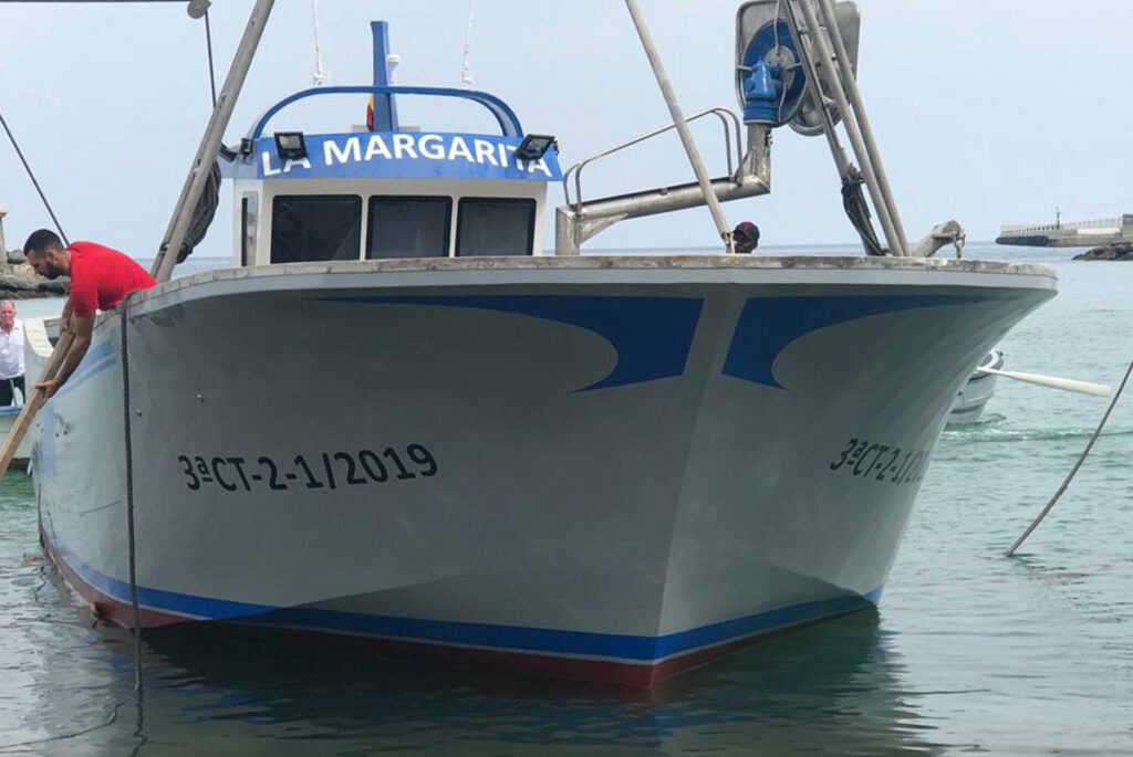 Vista frontal del barco de pesca La Margarita navegando por el puerto marítimo.