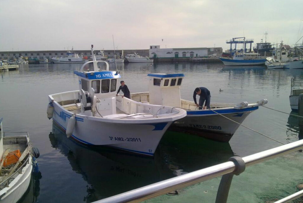 Amarre del barco de pesca Mi Amelia junto a otra embarcación en el puerto marítimo.