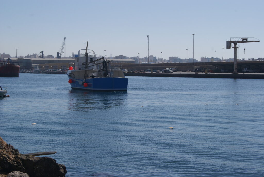 Vista trasera del barco de pesca Playa de Lancón navegando por el puerto.